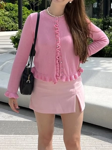 Close-up of pink knit cardigan with ruffle trim and matching slit skirt for resort wear
