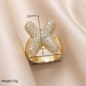 Macro detail of gold-plated X-shaped ring with zircons showing 18mm inner diameter