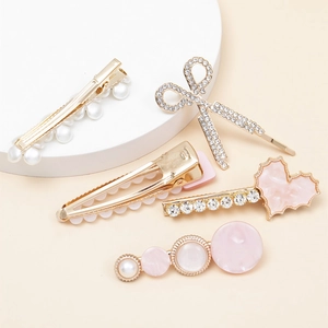 Detailed close-up of 5 gold-tone hair clips with pearls, rhinestones and feather designs