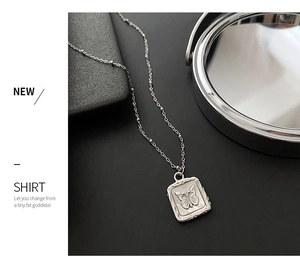 Detailed view of silver butterfly shell pendant on beaded chain over a black background