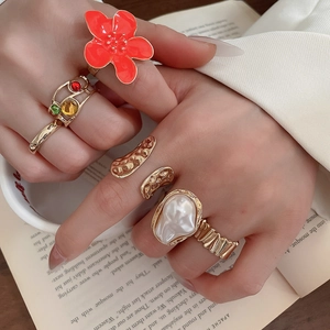 Detail of vintage gold flower rings set with pearls and enamel on an open book background