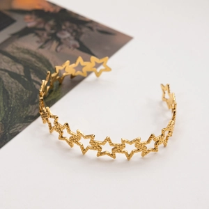 Macro detail of gold hammered stainless steel bangle with open star cutout pattern