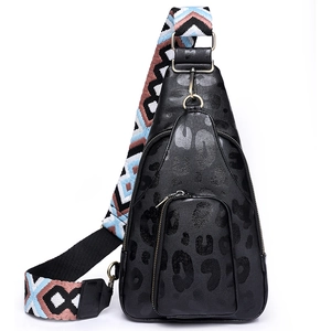 Close-up of black leopard print crossbody bag with colorful geometric woven strap detail