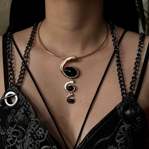 Macro shot of gold neck ring with triple spiral black resin oval pendant detail