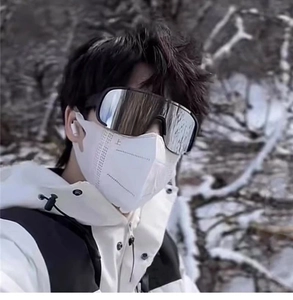 Outdoor selfie view of large frame cycling goggles with silver reflective lens on snowy background