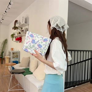 Neceser de flores con cremallera sostenido por modelo en una habitación luminosa