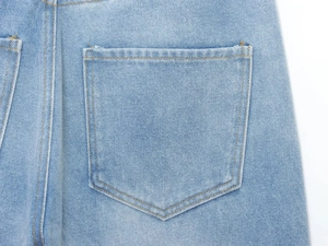 Détail de la couture de poche arrière sur gilet en jean bleu clair avec fil contrasté