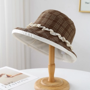Plaid sun hat for women with white lace trim on wooden stand with aesthetic background