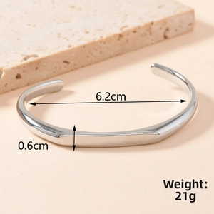 Detailed close-up of an irregular stainless steel cuff bangle with a smooth silver finish