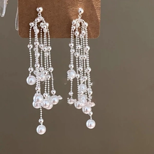 Macro shot of silver tassel earrings with delicate white pearls on a display card