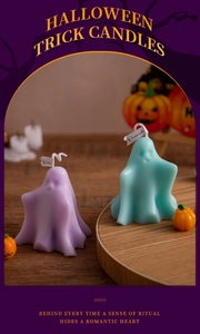 Detail of Halloween ghost and pumpkin scented candles on a wooden tray with festive decor