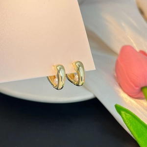 Gros plan de boucles d'oreilles dorées en U avec perles sur fond de soie élégant