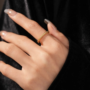 Detail of vintage gold beaded ring on fingers with black velvet background macro view