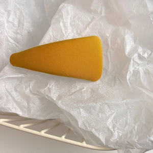 Macro shot of a yellow triangular sponge hair clip on textured white tissue paper