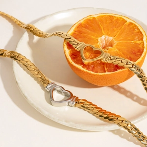 18K gold plated titanium steel necklaces with heart clasps on a white ceramic plate