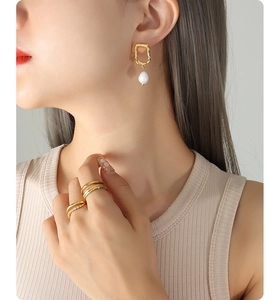 Detail of 18K gold-plated irregular geometric earrings with pearl and stacked rings