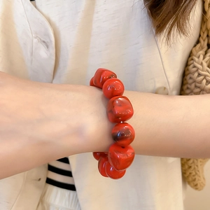 Détail d'un bracelet en perles d'acrylique rouge avec texture marbrée