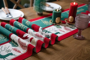 Close-up of red and green Christmas table runner with reindeer motifs and tassel details