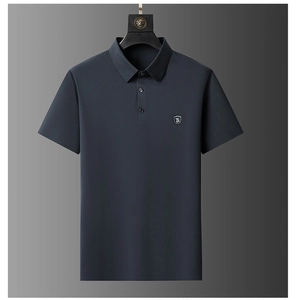 Close-up of the TB shield embroidery on the dark blue polo shirt chest detail