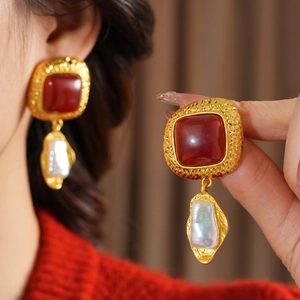 Detail of vintage square red stone and baroque pearl earrings with hammered gold finish