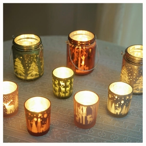Close-up of frosted Christmas glass candle holders with reindeer and tree patterns