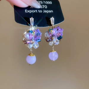 Close-up of bohemian purple crystal flower earrings with white pearl and gold tassels