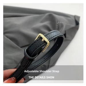 Detail of adjustable black leather shoulder strap with gold metal buckle and texture