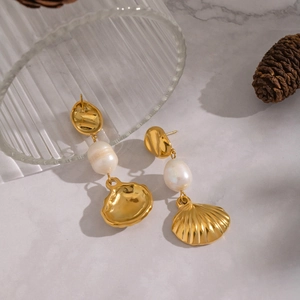 Detailed macro view of 18K gold plated shell pendant earrings with white freshwater pearls