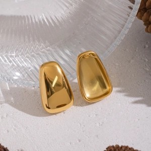 Polished golden geometric square stud earrings on stone texture with decor