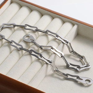 Detailed close-up of a silver geometric link chain necklace on a white velvet display