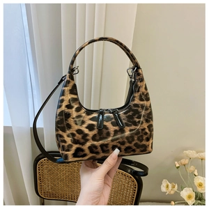 Detail of glossy leopard print patent leather bag with silver zippers and hand strap