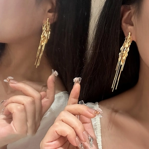 Eleganti orecchini a nappa di grano dorati in stile vintage indossati da una modella