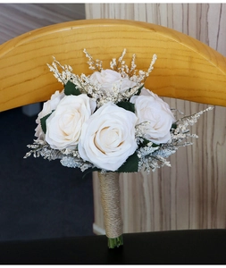 Detail of white artificial rose bridal bouquet with twine wrapped handle on wood