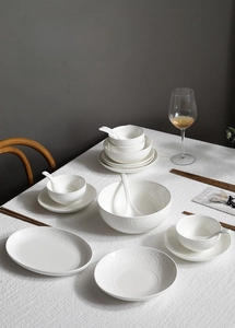 Detailed view of white embossed ceramic dinnerware set with elegant floral relief patterns