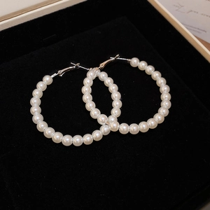 Detail shot of white pearl hoop earrings with silver pins in a black velvet jewelry box