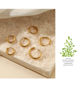 Set of six polished gold stainless steel hoop earrings displayed on a natural stone slab