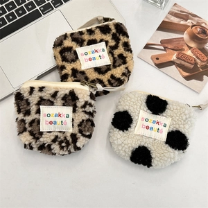 Flat lay of plush heart-shaped coin purses with leopard and cow prints on a desk