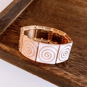 Macro detail of vintage elastic bracelet with rose gold squares and spiral enamel inlay