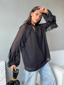 Detail of elegant black chiffon blouse featuring ruffled edges and flare sleeves