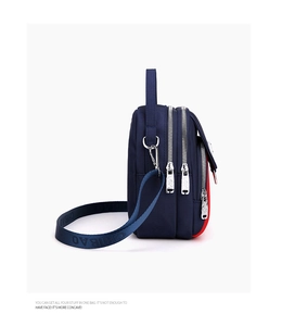 Side view of navy blue nylon crossbody bag featuring a triple-zipper layered design