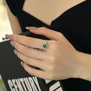 Macro detail of a silver four-leaf clover ring featuring green stones and small white diamonds