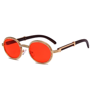 Vintage round sunglasses with red lenses and colorful rhinestone trim on wood grain temples