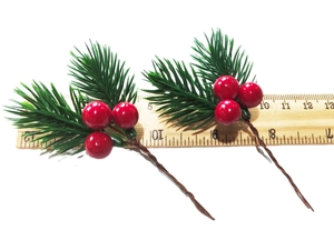 Detail of 13cm artificial pine needles with red berries on a ruler for size reference