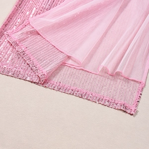 Dettaglio macro di paillettes rosa e tulle a pieghe su una gonna con spacco sexy