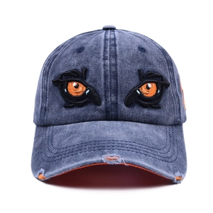 Distressed blue washed denim baseball cap featuring embroidered eyes and orange lining