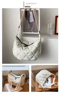 Detail of white quilted hobo bag featuring half-moon shape and wide shoulder strap