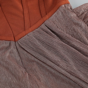 Dettaglio in maglia bordeaux unita a tessuto plissettato bronzo metallizzato e cuciture fini