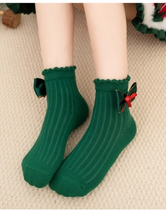 Detail view of green ribbed cotton socks with delicate lace trim and festive ribbon bows