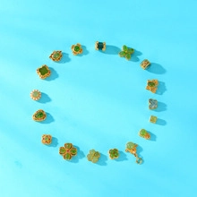 Detail of green clover, heart, and floral pendants with gold bases on blue background