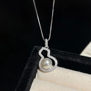 Macro shot of silver necklace with gourd pendant featuring white pearl and small diamonds